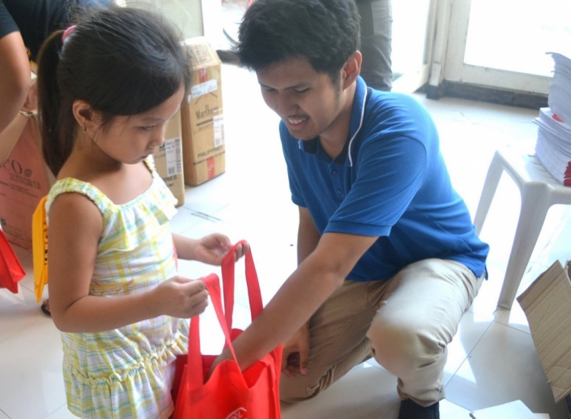 A KAIROS band member gives school supplies to a child during the Off-the-Street, On-to-School project (Photo by GABAY)